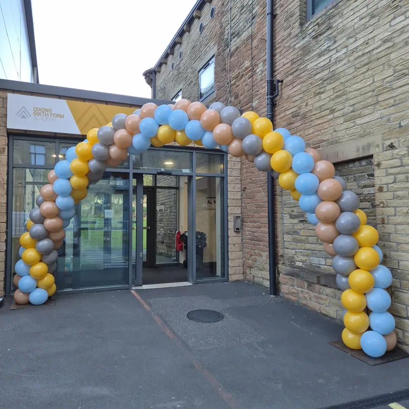 Pastel outdoor balloon arch at a sixth form academy entrance