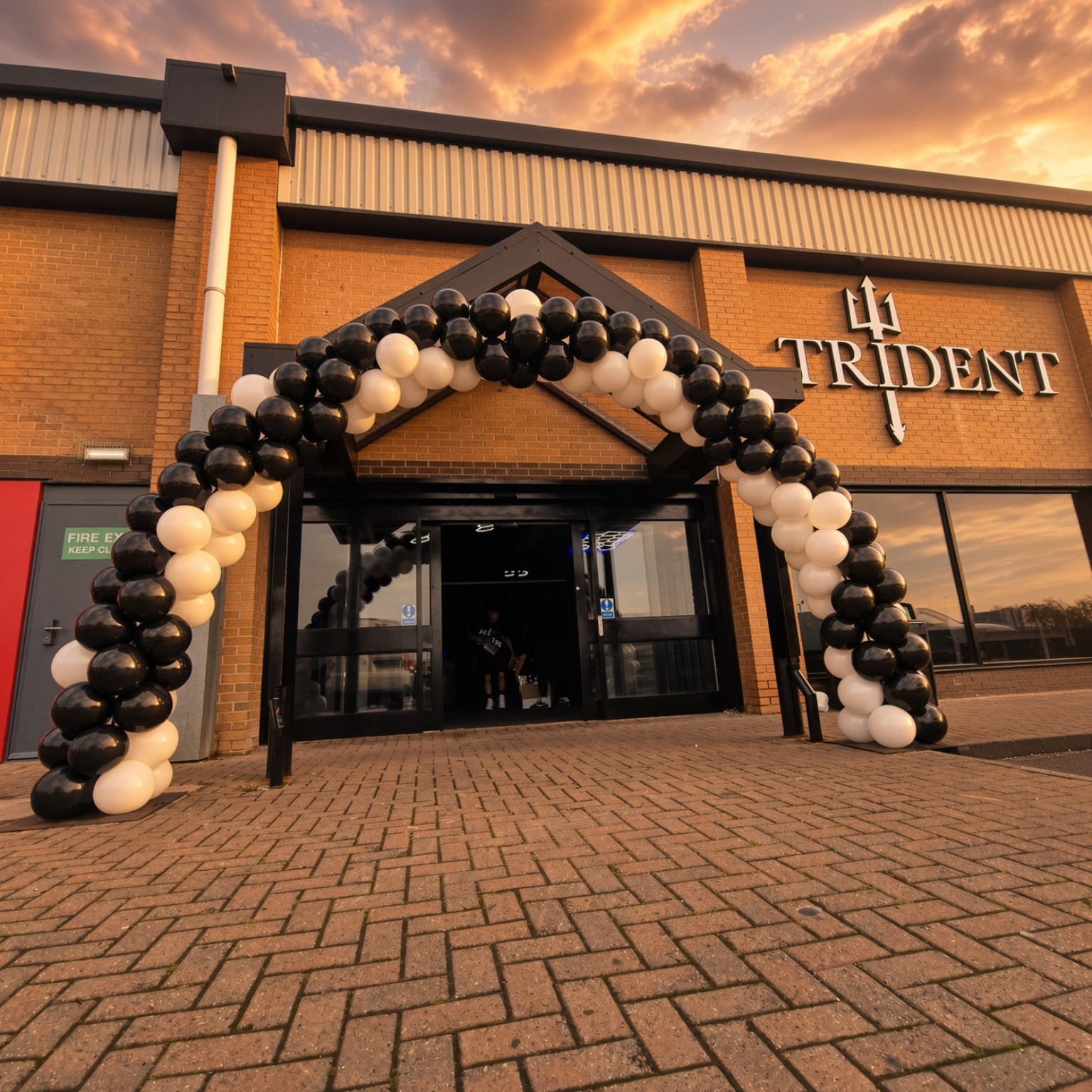 Large black and white outdoor balloon arch at a business entrance