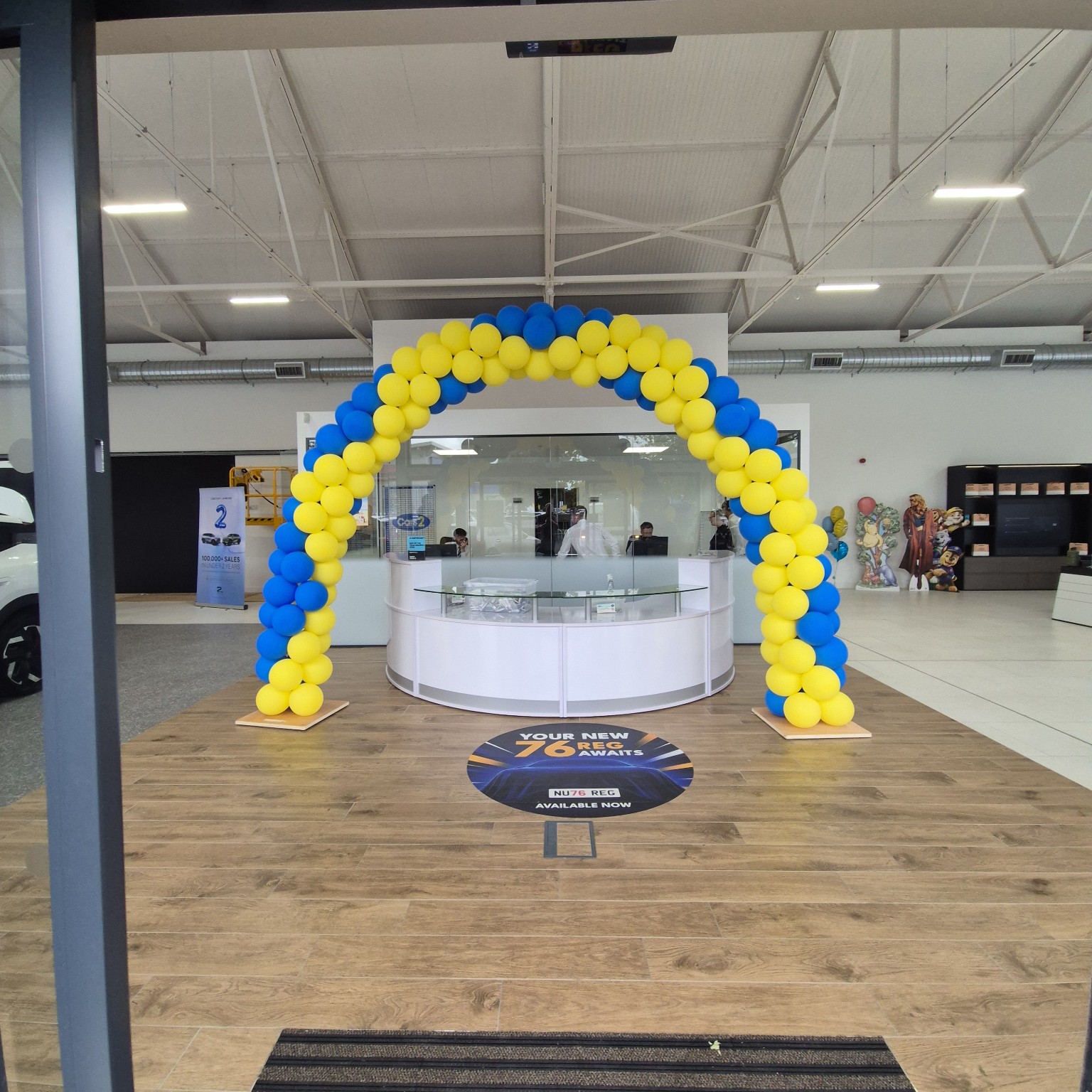 Blue and yellow balloon arch in a car showroom
