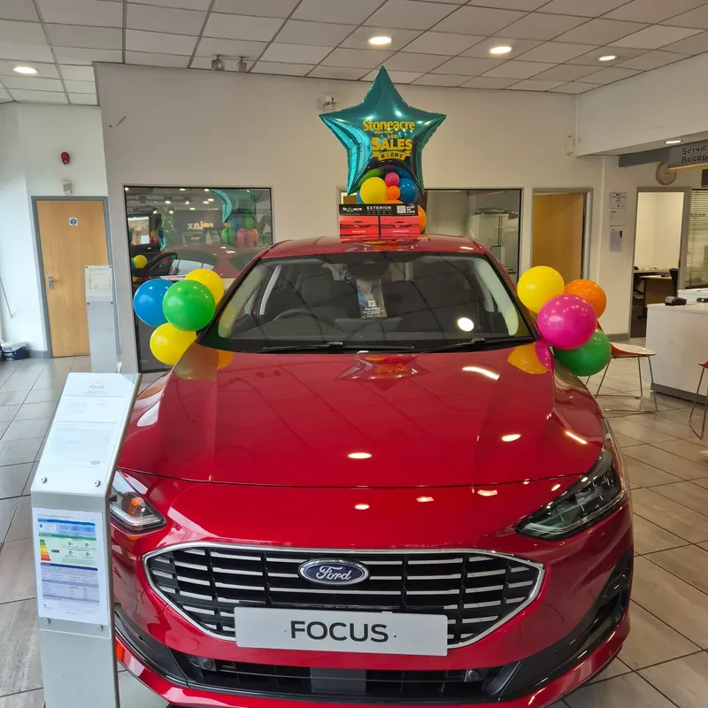 Balloon topper and mirror bows on a showroom car